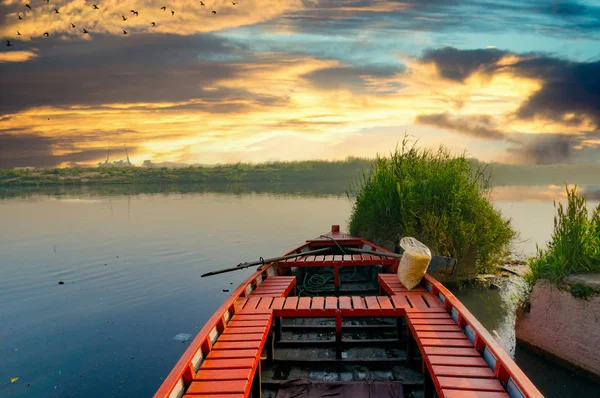 Barco vermelho vazio ancorado perto de alguns arbustos em um rio azul sereno — Fotografia de Stock