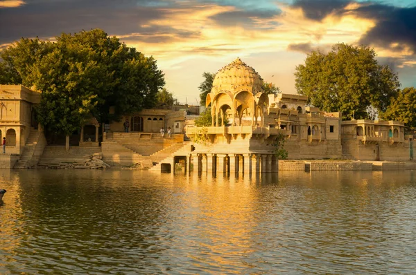 Cúpulas de arenito chattri com passos no lago gadi sagar em jaisalmer ao entardecer — Fotografia de Stock