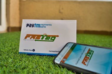 Hızlı Etiket Paytm Ödeme Bankası tarafından yeşil çimenler üzerinde hızlı etiket web sitesine bağlanmış bir cep telefonuyla sağlandı.