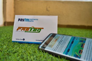Hızlı Etiket Paytm Ödeme Bankası tarafından yeşil çimenler üzerinde hızlı etiket web sitesine bağlanmış bir cep telefonuyla sağlandı.