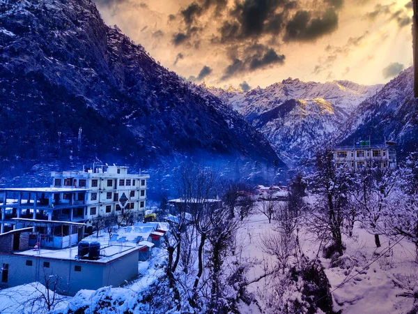 Building in the middle of the mountains covered with a lot of snow during sunrise with the sky shining golden