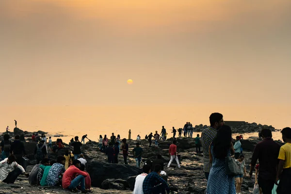 Oamenii de pe plaja stâncoasă se bucură de apusul soarelui — Fotografie, imagine de stoc