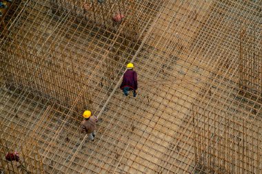 Hindistan 'da inşaat işçileri bir demirin üzerinde dikiliyorlar bar platformunu güçlendirerek sütun yapıyorlar.