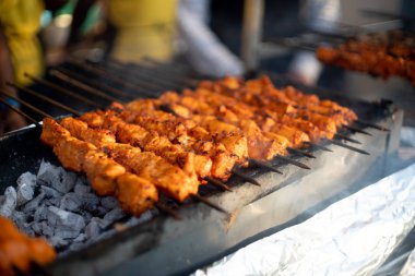 Paneer balıklı tavuk tikka açık bir ocakta kızarıyor. Parlayan kömürleri ve çıkan dumanla birlikte.