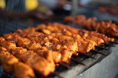 Paneer balıklı tavuk tikka açık bir ocakta kızarıyor. Parlayan kömürleri ve çıkan dumanla birlikte.