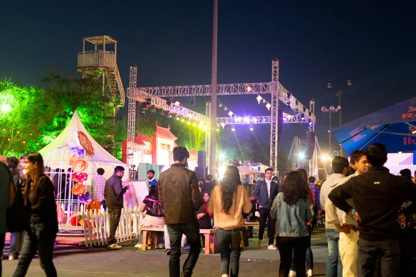 Men women roaming around enjoying the stage music performance in the background and the decorations all around them — Stock Photo, Image