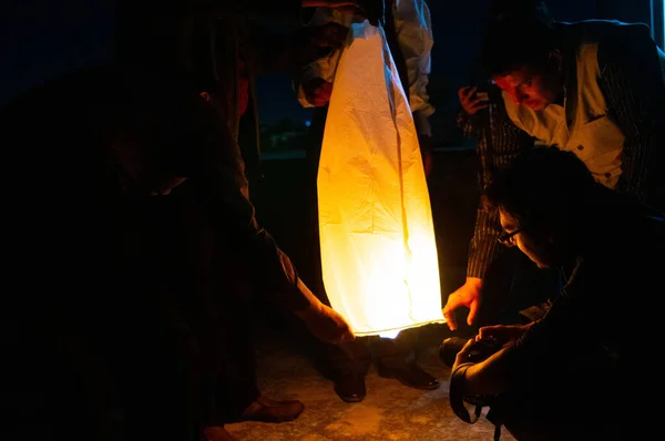 Les gens tenant une lanterne jaune avec les flammes montrant clairement — Photo
