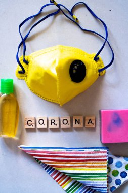 Tahta bloklu düz tabaka Corona, sarı yüz maskesi, dezenfektan ve coronavirüs güvenliği için sabun.