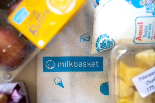 Flatlay image of multiple home essentials like milk, butter, fruits and bread coming from a milkbasket bag which provides a daily subscription delivery of groceries — Stock Photo, Image