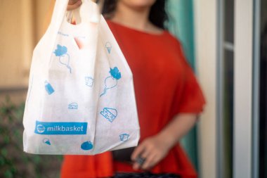Indian woman girl holding up a milkbasked bag with daily subscription home delivery with face hidden clipart