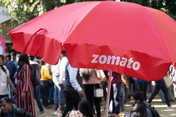Umbrlla με το εμπορικό σήμα Zomato και τα χρώματα με εκτός εστίασης πλήθος πίσω τους — Φωτογραφία Αρχείου