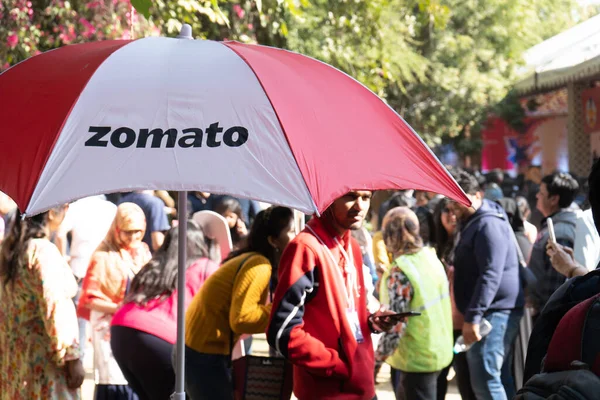 Umbrlla με το εμπορικό σήμα Zomato και τα χρώματα με εκτός εστίασης πλήθος πίσω τους — Φωτογραφία Αρχείου