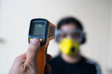 Kızılötesi temas olmayan termometre, şehir tecritten kurtulup yavaş yavaş işine geri dönerken gözlük takan ve maske takan Hintli genç bir kızı kontrol etmek için kullanılıyor.