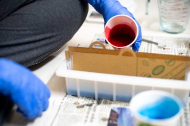 Mavi eldivenli el, kağıt bardaktan kırmızı sıvıyı kalıba döküyor. Küçük endüstriler için ev yapımı sabun yapımında kullanılıyor. Hatta evde hobi olarak bile kullanılıyor.