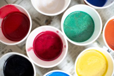 Kağıt bardaklardaki renkli sıvının genel karesi sabun, gıda rengi ve ev yapımı el sanatları veya zanaatkar ev sanayileri için boyaları gösteriyor.