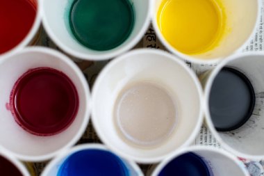 Kağıt bardaklardaki renkli sıvının genel karesi sabun, gıda rengi ve ev yapımı el sanatları veya zanaatkar ev sanayileri için boyaları gösteriyor.