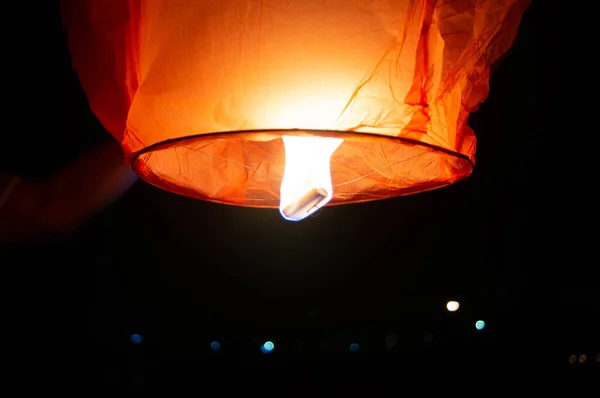 Person holding a red sky lantern with the flames showing clearly — Stock Photo, Image