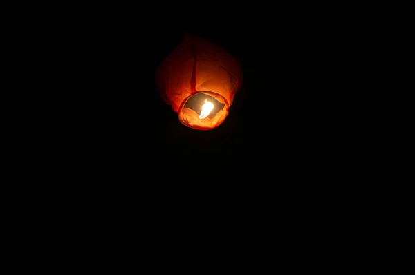 A red coloured sky lantern with the flames showing clearly lifiting off — Stock Photo, Image