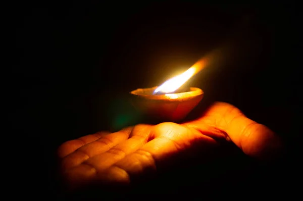 Lit diya o lámpara de arcilla en la palma de una persona — Foto de Stock