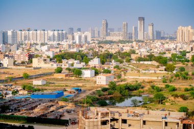 Delhi, Hindistan - 2020 dolaylarında: İnsanlar uzaktaki modern binaların bulunduğu gecekondu mahallelerinde yaygın bir el pompası kuyusu tankında banyo yapıyorlar