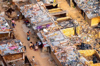 Delhi, Hindistan - 2020 dolaylarında: Kırık tuğlalarının ve teneke evlerinin dışında oturanların etrafı pislik ve çöplerle dolu bir gecekondu mahallesinde havadan çekilmiş görüntüleri. Tuğla duvarları ve teneke çatıları tuğlalarla, ağır çantalarla ve daha fazlasıyla bir arada gösteriyor