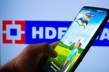 Jaipur, Hindistan, Circa 2020 - HDFC bankasının mobil uygulamasına HDFC banka yönetim kurulu önünde giriş yapan bir cep telefonu. Arka plan parlak bir şekilde ışıklandırılmış. Ekran mobil uygulamanın oturumunu gösterir.