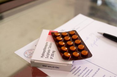 Bir kutu ve hidrokloroksit sülfat tabletlerinin fotoğrafları kağıdın üzerinde bir kalem olan beyaz reçeteli bir kağıt üzerinde..