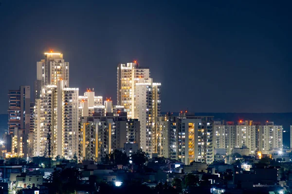 cluster of sky scraper buildings at night with golden lights shot on a pollution free night in gurgaon delhi. Shows buildings with residences and offices showing the rapid growth of the real estate sector and companies coming to India in metro cities