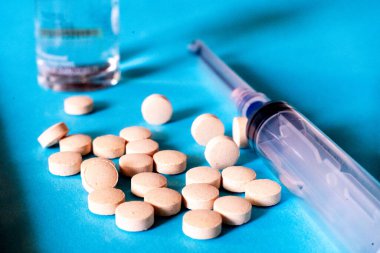 Mavi arka planda cam ampul, şişe, tablet, şırınga ve şırınga görüntüsü, covid19 koronavirüsün tedavisinde antiviral olarak kullanılan ilaç ve tedavileri göstermektedir..