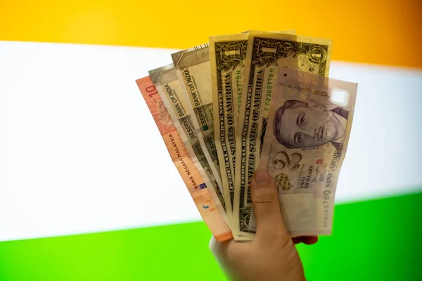 通貨ノート米ドル、インドルピー、マレーシア・リンギット、シンガポール・ドルなどの混合物を外国為替の概念を示すインドの国旗の前で手を握る — ストック写真