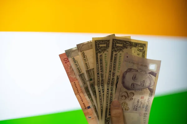 通貨ノート米ドル、インドルピー、マレーシア・リンギット、シンガポール・ドルなどの混合物を外国為替の概念を示すインドの国旗の前で手を握る — ストック写真