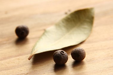 Arkaplanda defne yaprakları olan ahşap bir masada baharatlı bezelye.