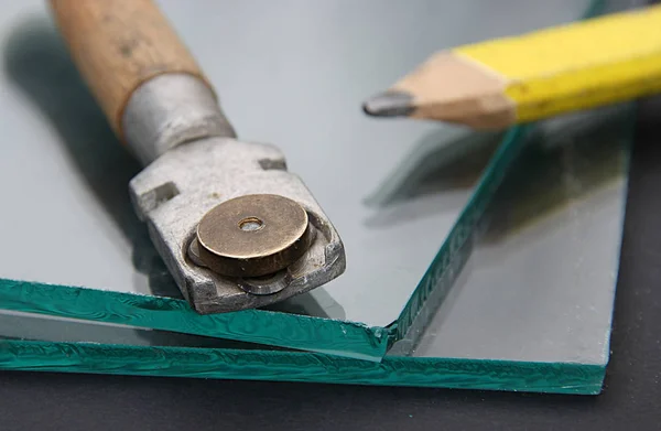 Glass cutter on the background of window glass and pencil