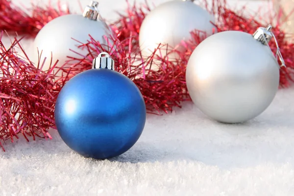 Christmas toy blue ball on a background of silver balls in the snow