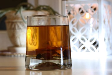 Bir mumun arka planında kurumuş meyve kompostosu ve çiçekli bej bir kap.