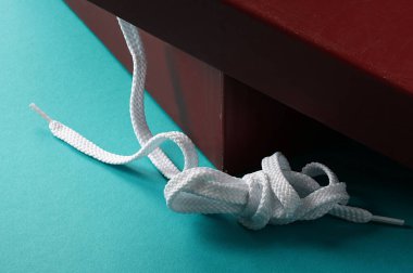 Turkuaz arka planda beyaz ayakkabı danteli ve kahverengi kutu.