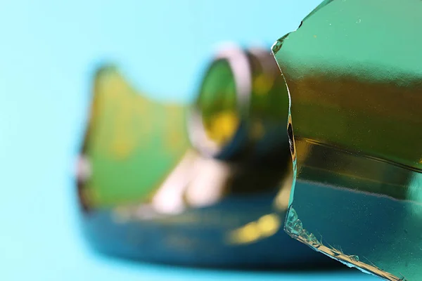 Shattered glass bottles of green on a turquoise background