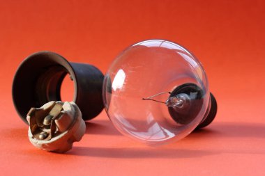 Yanan ampul ve kırmızı arka planda eski kartuşlar.