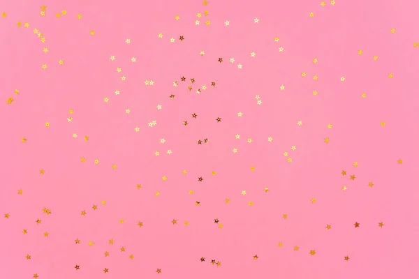 Altın renkli yıldızların fotoğrafı pembe modaya uygun arka planda parıldıyor. Projeleriniz için şenlikli tatil geçmişi. Kutlama konsepti. Noel deseni. Üst manzara, düz uzanma