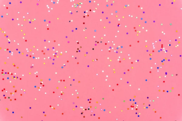 다양 한 색깔의 별들의 사진 이 핑크 색의 유행하는 배경 위에 반짝 이는 스프링 클링을 하고 있다. 당신의 프로젝트를 위한 즐거운 휴일 배경. 축하하는 컨셉. 크리스마스 패턴. 위에서 본 전경, 평평 한 면 — 스톡 사진