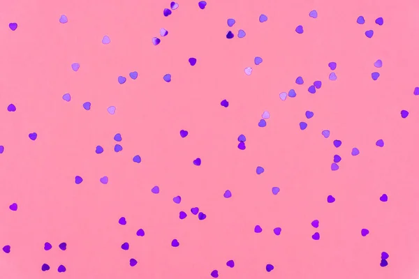 Zdjęcie purpurowe serca błyszczące posypki na różowym modnym tle. Uroczyste tło świąteczne dla Twoich projektów. Koncepcja świętowania. Wzór miłości. Widok z góry, płaski — Zdjęcie stockowe
