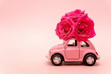 Severodvinsk, Rusya, 14 Aralık 2019: pembe arka planda gül çiçekleri getiren pembe retro oyuncak araba. 14 Şubat, Sevgililer Günü, 8 Mart, Uluslararası Kadınlar Günü. Çiçek teslimatı