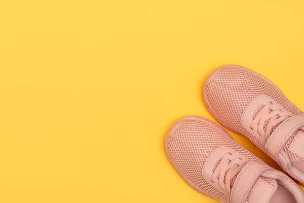 Pink sport shoes on yellow background. New sneakers on yellow pastel background. Losing weight and sport concept. Top view, flat lay, copy space