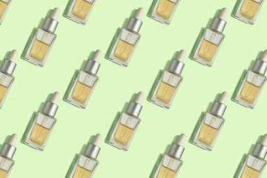 Cam şişedeki yaşlanma önleyici serumun kusursuz deseni ve pastel arkaplanda damlatıcısı. Yaratıcı düzen, kozmetik kusursuz desen, düz döşeme. Paketleme tasarımı, kumaş, kağıt üzerine baskı