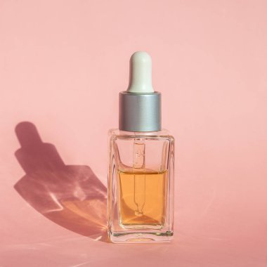 Cbd kenevir yağı, marihuana yağı şişesi ve pastel pembe arka planda sert ışık yansıması. Tıbbi marihuana konsepti, doğal bitki. Kapatın. Kare İnstagram biçimi