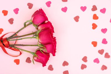 Pembe gül çiçekleri ve yumuşak pembe arka planda kalp şeklinde kağıt konfeti. Doğum günü, anneler, sevgililer günü konsepti. Tatil geçmişi. Düz konum, üst görünüm, kopyalama alanı.