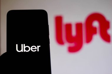 11 Aralık 2019. Bu resimde Uber logosu bir akıllı telefon ve bulanık arka planda Lyft logosu üzerinde görüntülenir
