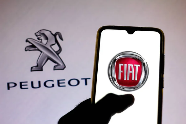 19 december 2019, Brazilië. In deze foto illustratie is het Fiat Automobiles logo te zien op een smartphone en Peugeot logo op de wazige achtergrond — Stockfoto