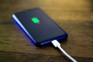 Akıllı telefon ahşap masanın aküsünü şarj ediyor.