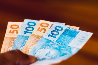 Adamın elinde 150 reais banknot var. Brezilya para ve ekonomi ve finans kavramı